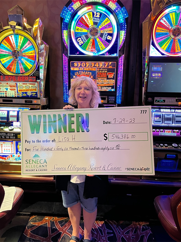 A woman holding a check for $546,386 won on IGT's Wheel of Fortune Ultimate Sevens wide area progressive slot game. 