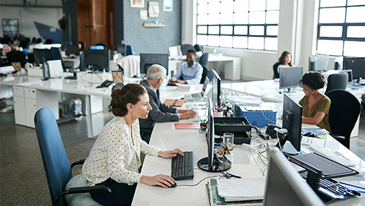 A group of people in an office using computers to connect with IGT's customers and provide best-in-class service. 