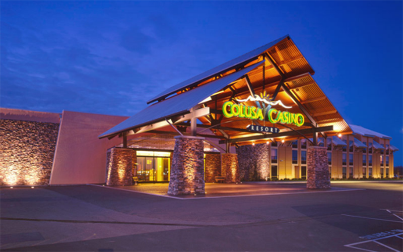 The outside of a casino at dusk with stone and concrete walls and golden lighting