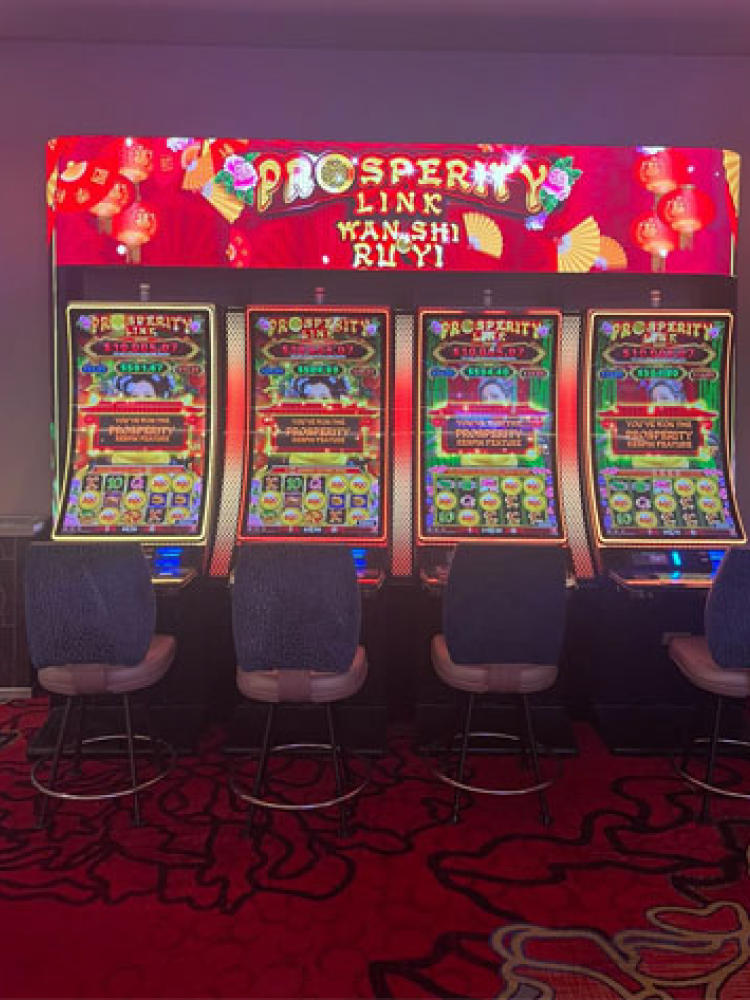 A bank of four slot machines featuring IGT's Prosperity Link Wan SHi Ru Yi  on a casino fllor.
